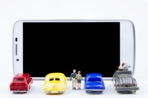 Miniature cars lined up against a phone screen